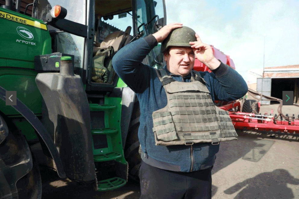 Ukrainian farmer putting on helmet and flak jacket before getting in the tractor Image